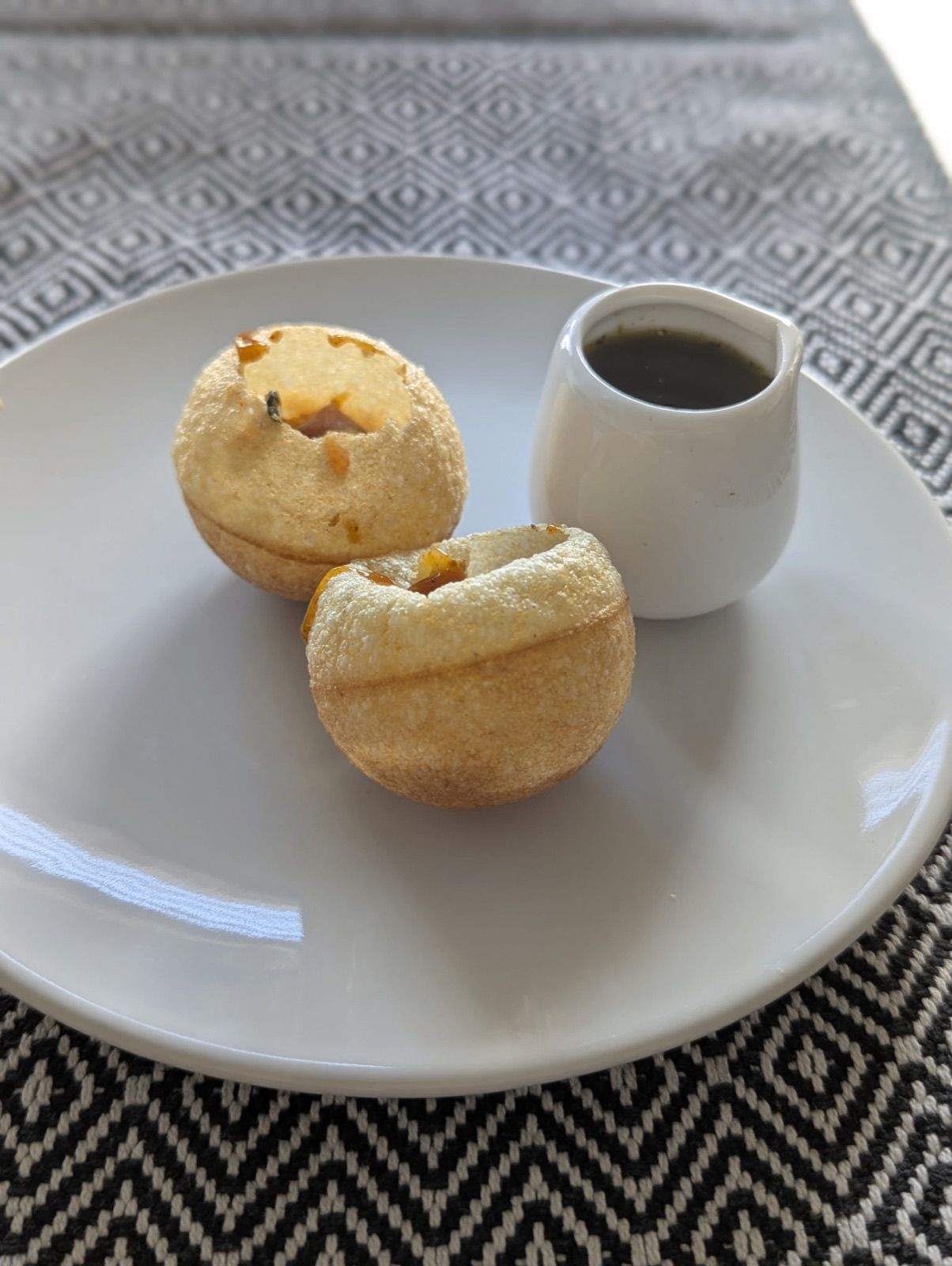 Pani puri served on a plate with a jug of spiced water