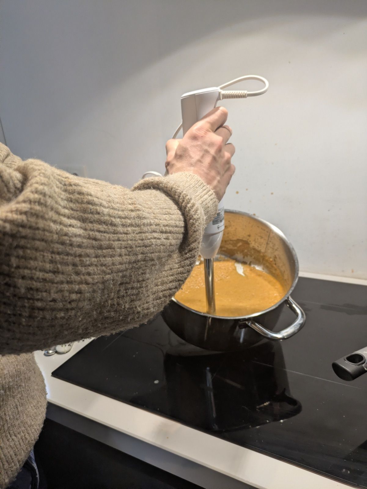 A hand blending the curry base with a stick blender during a workshop